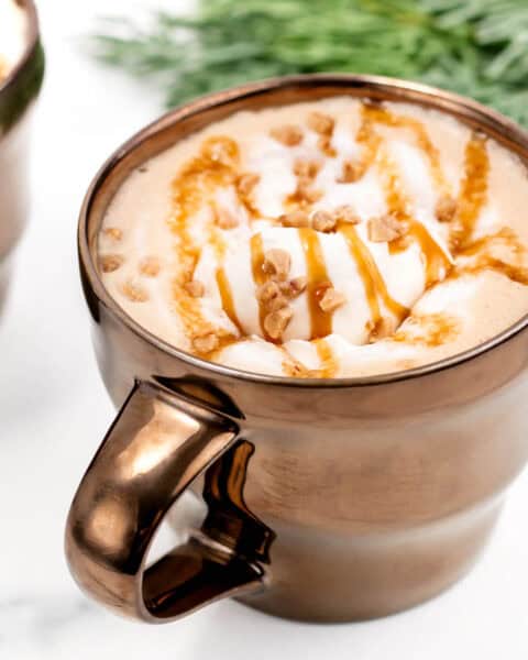 A caramel brulee latte with whipped cream and caramel it.