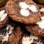 A tin of chocolate cookies with marshmallows on top.