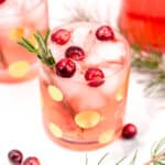 Two glasses with cranberries and sprigs of spruce.