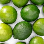 A bunch of green limes on a white background.