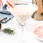 Two martinis with whipped cream and candy canes.