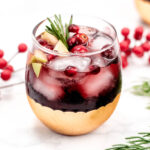 A festive glass of cranberry mulled wine with a sprig of rosemary, perfect for Christmas celebrations.