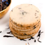 A stack of cookies next to a bowl of tea.