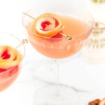 Two glasses of blonde cocktail with a slice of grapefruit.