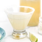 A Homemade Margarita in a glass next to a bottle of tequila.