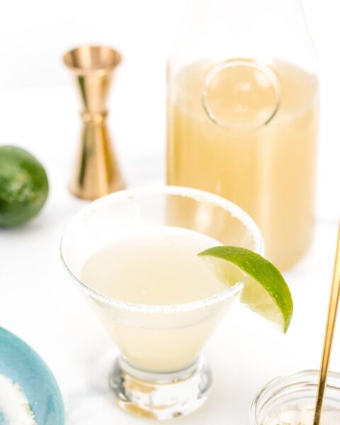 A homemade margarita in a glass with a lime wedge.
