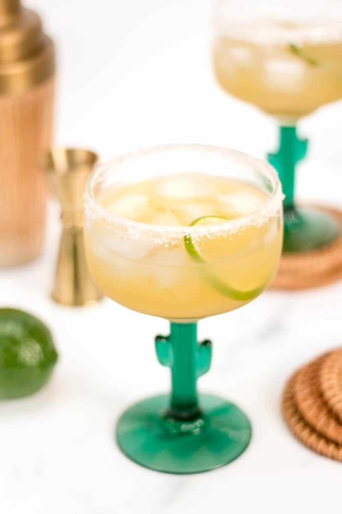 Two margarita glasses with limes and lime wedges, perfect for enjoying a refreshing Virgin Margarita.