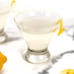 A glass of lemonade with a slice of lemon next to it.