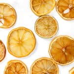 Sliced and dried citrus fruit arranged on a white surface.