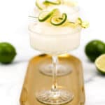 Two margarita cocktails with lime garnish on a golden tray.