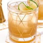 Two glasses of a drink with a lime and cucumber garnish.