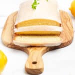 A slice of lemon cake on a wooden cutting board.