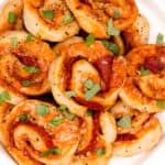 A plate of pizza pinwheels garnished with fresh herbs.