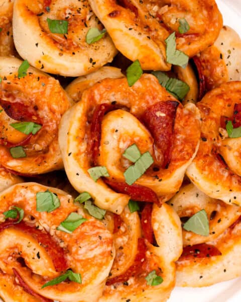 A plate of pizza pinwheels garnished with fresh herbs.