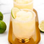 Two virgin frozen lime margaritas with garnish on a golden tray.