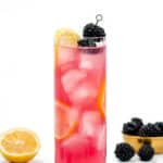 A refreshing Oaks Lily cocktail with ice, lemon slices, and whole blackberries on top, served in a tall glass.