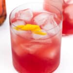 Two glasses of red iced tea garnished with lemon slices on a white background.