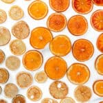 Slices of dried citrus fruits, including oranges and lemons, arranged in a pattern on a white background.