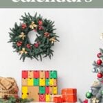 A decorative holiday scene with a wreath, Food Advent Calendars, wrapped gifts, and part of a Christmas tree beside a white dresser. Text reads “advent calendars.”.