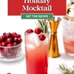 A festive cranberry mocktail garnished with cranberries and rosemary, with cocktail tools and fresh cranberries in the background.