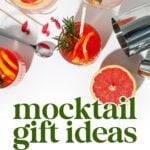 Top view of colorful mocktails with citrus slices and herbs, a cocktail shaker, and text reading "mocktail gift ideas: what to get a mixologist.