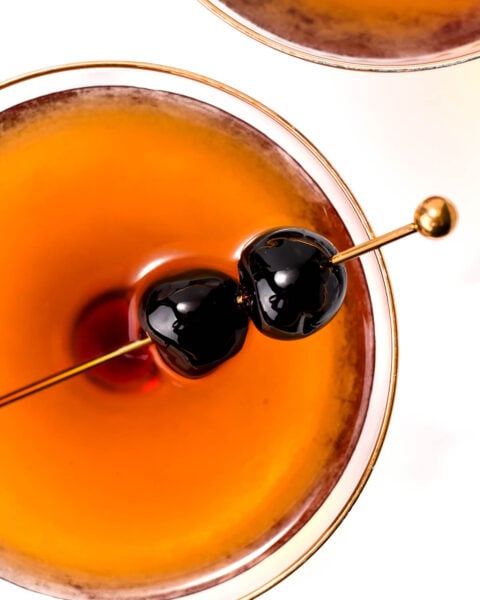A cocktail with two cherries on a skewer, viewed from above.