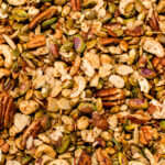 A close-up of a mixed nuts assortment, including cashews, pecans, pistachios, pumpkin seeds, and walnuts.