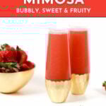 Two gold-rimmed glasses brimming with luscious Strawberry Mimosas sit beside a bowl of ripe strawberries. Text reads: "Strawberry Mimosa: Bubbly, Sweet & Fruity. Get the recipe at feastandwest.com.