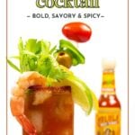 A Bloody Mary cocktail garnished with celery, shrimp, olives, a lime wedge, and a cherry tomato, with a bottle of hot sauce in the background.