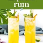 Two tall glasses filled with a yellow Summer Cocktail, ice, mint, and lime wedges sit on a white surface, with the text “how to pick the perfect rum” above.