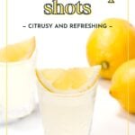 A glass of lemon drop shot garnished with a lemon wedge and a splash of Hibiscus Syrup, with whole lemons in the background and text overlay promoting the drink.