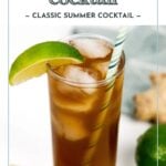 A tall glass of dark and stormy cocktail with ice, a striped straw, and a lime wedge garnish.