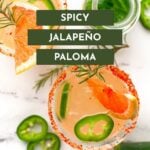 Two glasses of spicy jalapeño Paloma cocktails with grapefruit, jalapeño slices, and chili-rimmed glasses on a white surface, next to a bottle and jalapeño slices. Text overlay: "Spicy Jalapeño Paloma.