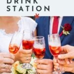 Four people hold glasses of red iced wedding cocktails at a celebration, with the bride’s bouquet and the groom in a suit and red tie visible in the background.