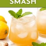 A glass of whiskey smash cocktail garnished with mint, surrounded by lemons and ginger, with text promoting a recipe.