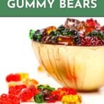 A bowl filled with colorful gummy bears sits on a white surface, with additional gummy bears scattered nearby. Text reads: "How to make alcoholic gummy bears. Get the recipe. feastandwest.com.