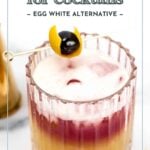 A layered cocktail with a frothy top in a glass, garnished with a cherry and lemon peel on a cocktail pick. Text reads: “aquafaba for cocktails – egg white alternative.”.