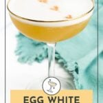 A cocktail in a coupe glass with a foamy top and cocktail bitters, next to a teal cloth. Text reads: “Egg White Alternative for Cocktails.”.