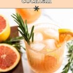 A glass of classic greyhound cocktail with ice, garnished with a rosemary sprig and grapefruit slice; grapefruit halves and rosemary are nearby.