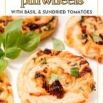 Close-up of golden brown Puff Pastry Pinwheels with herbs and sun-dried tomatoes, garnished with fresh basil on a white plate.