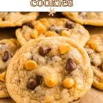 A close-up of butterscotch chocolate chip cookies on parchment paper, with chocolate and butterscotch chips on top.