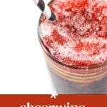 A glass of red slushy drink with a black and white striped straw, viewed from above. Text reads "cheerwine bourbon slushy.