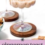 A cocktail in a decorative glass with a cinnamon sugar rim, placed on a wooden coaster, next to a bowl and pieces of cereal. Text reads "Cinnamon Toast Crunch Cocktail, three ingredients!.