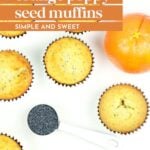 Overhead view of orange poppy seed muffins on a white surface, with a whole orange and a measuring spoon filled with poppy seeds.
