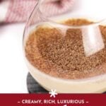 A glass of Cape Velvet cream liqueur topped with grated chocolate sits on a dark coaster, with a blurred red and white cloth in the background.