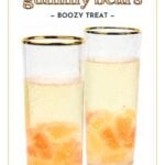 Two clear champagne flutes filled with champagne and orange gummy bears, set against a white background. Text on image reads "champagne gummy bears - boozy treat".