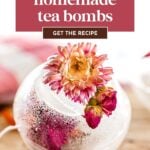 A clear ornament-shaped tea bomb filled with tea and dried flowers, with pink flowers attached, sits on a wooden surface. Text overlay promotes a homemade tea bombs DIY gift idea and recipe.