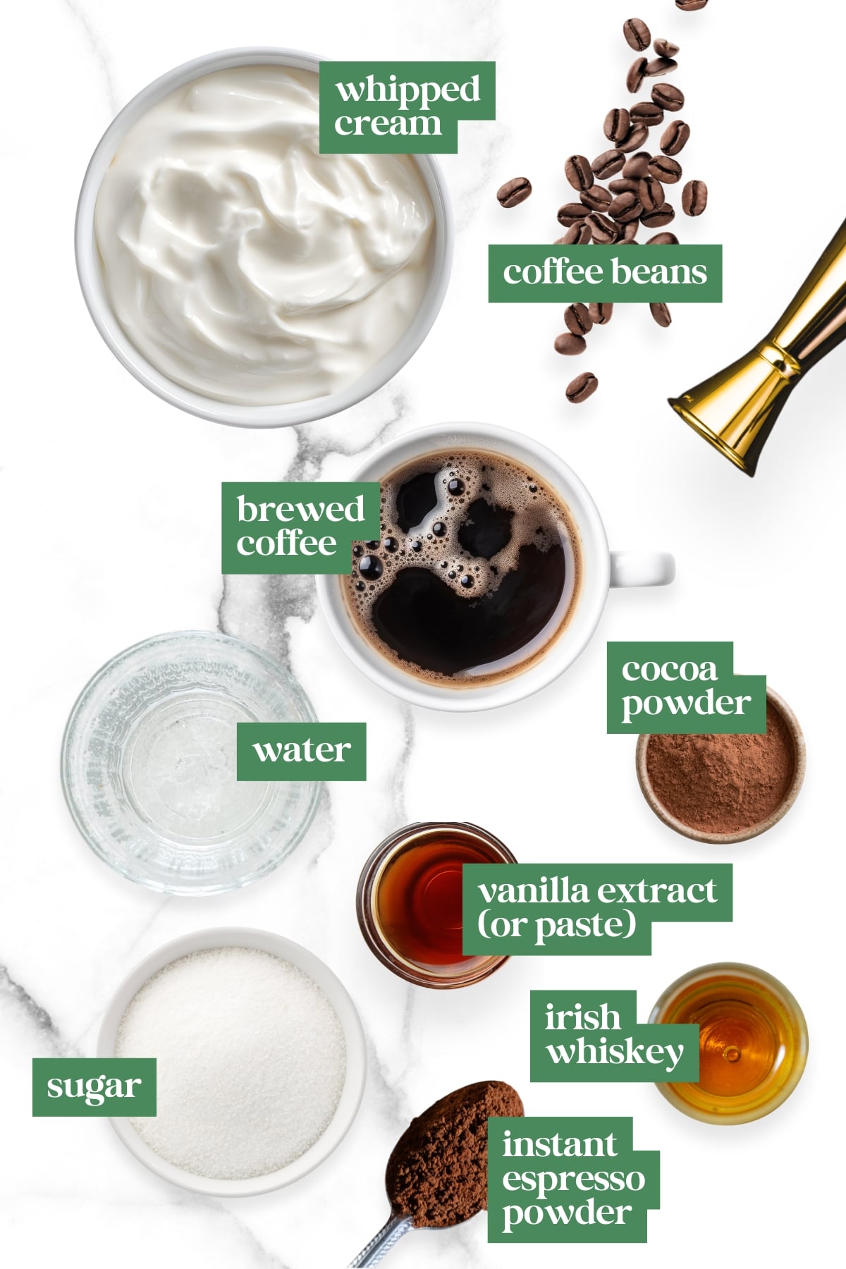 Top-down view of how to make Irish coffee: whipped cream, coffee beans, brewed coffee, water, cocoa powder, vanilla extract, Irish whiskey, sugar, and instant espresso powder are all artfully arranged.