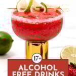 A bright red alcohol-free drink in a glass with a salted rim, garnished with lime and lemon slices, next to a lime and a strawberry. Text reads "17+ Alcohol Free Drinks.