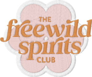 An embroidered patch with a pink flower shape and white border, featuring "Freewild Spirits Club" in bold orange thread, perfect for showcasing your Tripwire style.